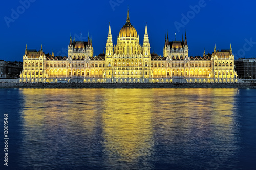 Evening view of the Hungarian Parliament Building in bright yellow illumination. View from the bank of Danube in Budapest, Hungary.