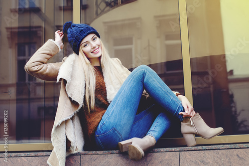 Outdoor full body portrait of young beautiful happy smiling girl posing on street. Model looking at camera. Lady wearing stylish winter clothes. Female fashion. Toned