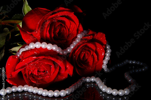red roses and white necklace on a black background