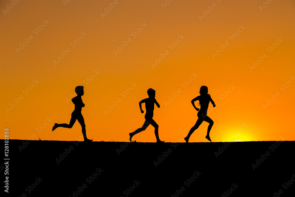 silhouette of kids running against sunset