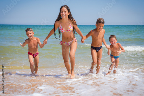 Four kids running from sea on beach