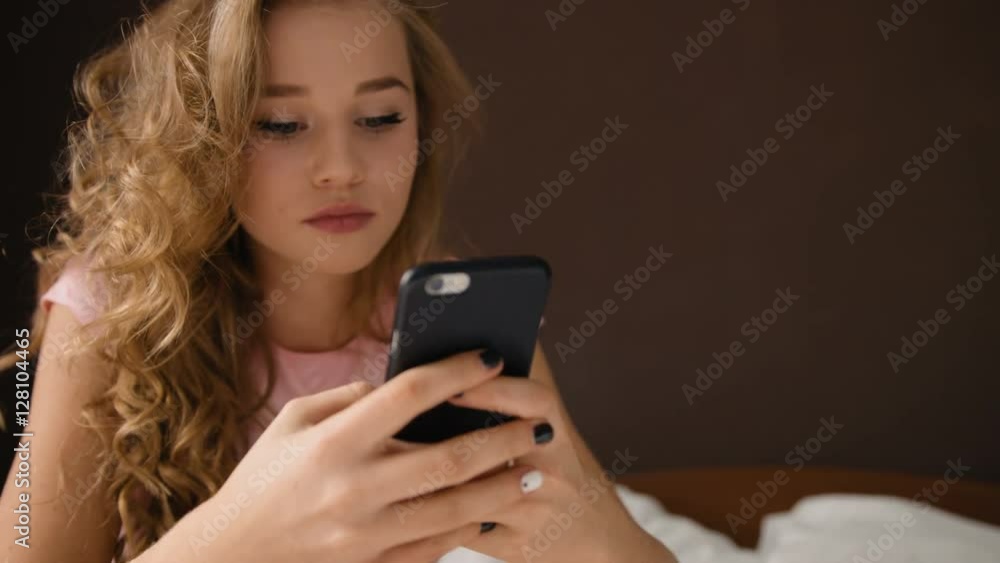 Attractive young beautiful girl chatting with her friends , while sitting on her bedroom. Attractive young beautiful girl chatting with her friends , while sitting on her bedroom.