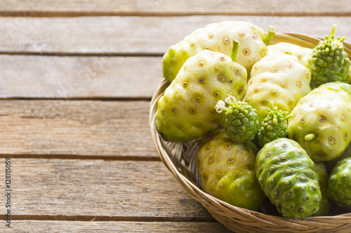 Noni fruit in the basket on wooden table.Fruit for health and herb for health.
