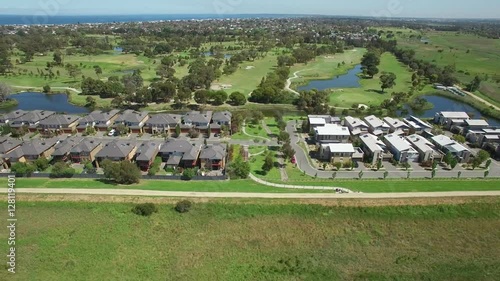 Aerial sweeping pan across typical Australian suburban houses and countryside on bright sunny day photo