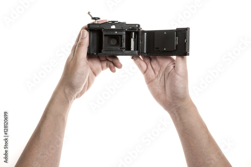 Two hands hold a vintage(old, classic) camera and open the cover for replace a film isolated white.  photo