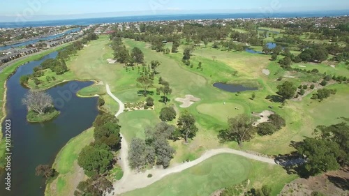 Forward flight over beautiful golf course with golfers playing on bright summer day photo