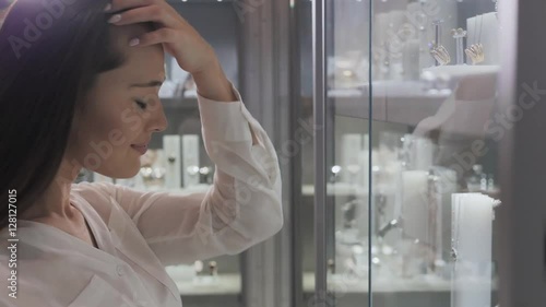 Beautiful young woman looking in a shop window with watches and luxury juwellery in shopping mallt photo