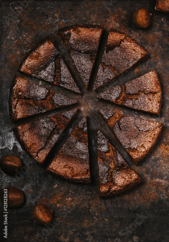 Flourless chocolate chestnut cake sliced into pieces on a dark rusty metallic background. Selective focus. Toned image 