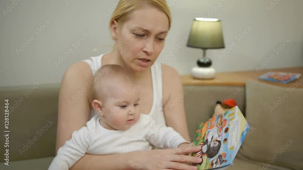 Mother 40 years old reading a book a small child sitting on the couch Mother 40 years old reading a book a small child sitting on the couch