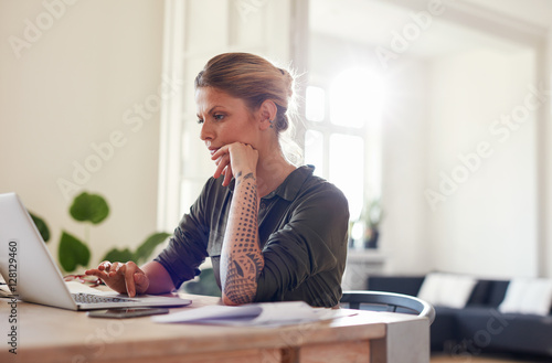Beautiful young woman sitting at home office using laptop