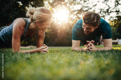 Fit young man and woman exercising in park