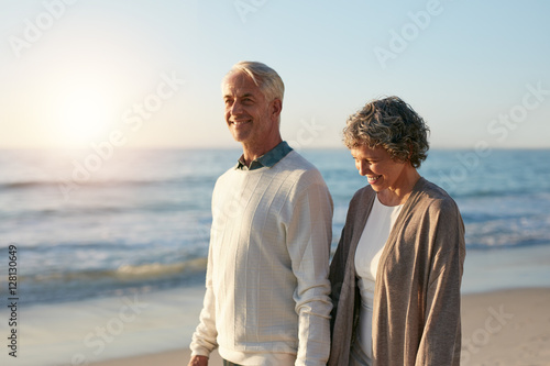 Happy mature couple walking along the beach