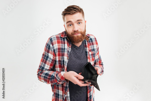 Upset young man holding empty wallet