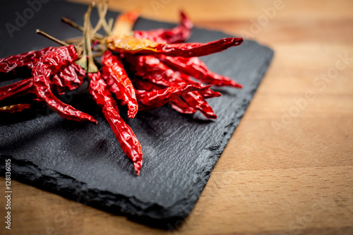 dried red chili pepper on slate on wooden background
