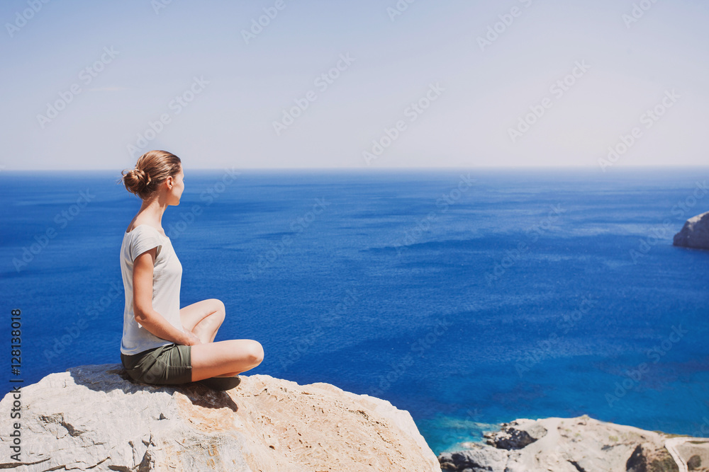 Young woman relaxing outdoors. Attractive girl sitting on the rock and looking at sea. Ralaxation and active lifestyle concept Young woman relaxing outdoors. Attractive girl sitting on the rock and looking at sea. Ralaxation and active lifestyle concept