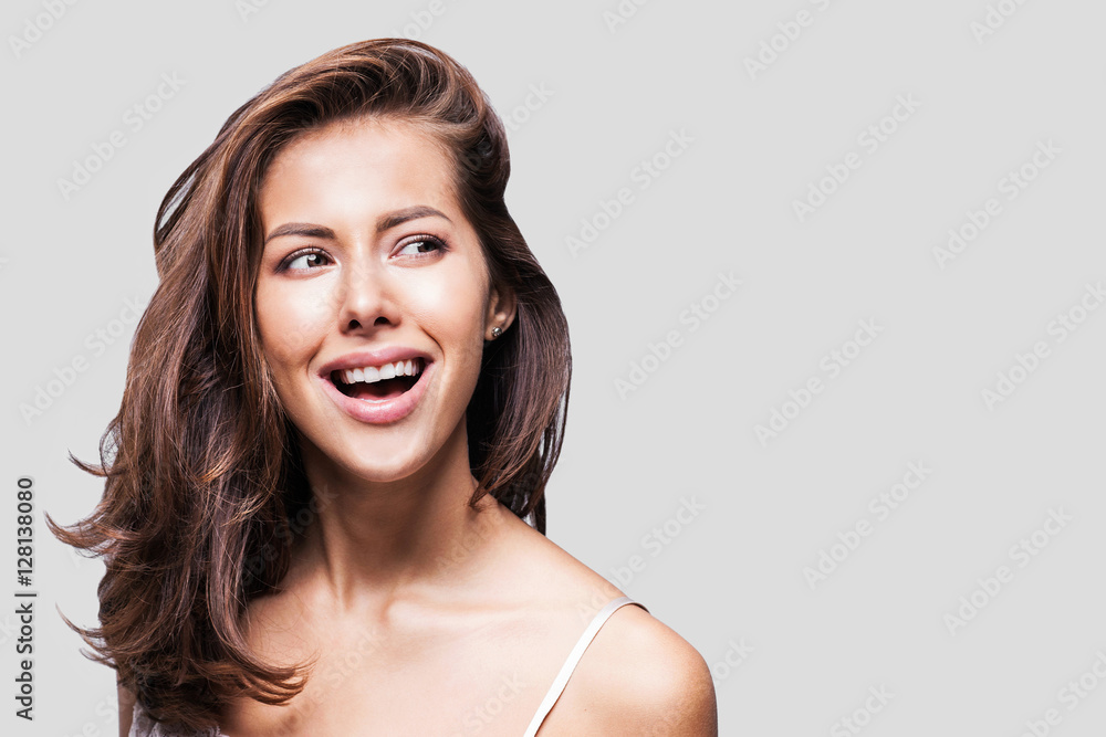 Fototapeta premium Studio portrait of a beautiful young woman with long brunette hair. Pretty spa model girl with perfect fresh clean skin. Youth and skin care concept