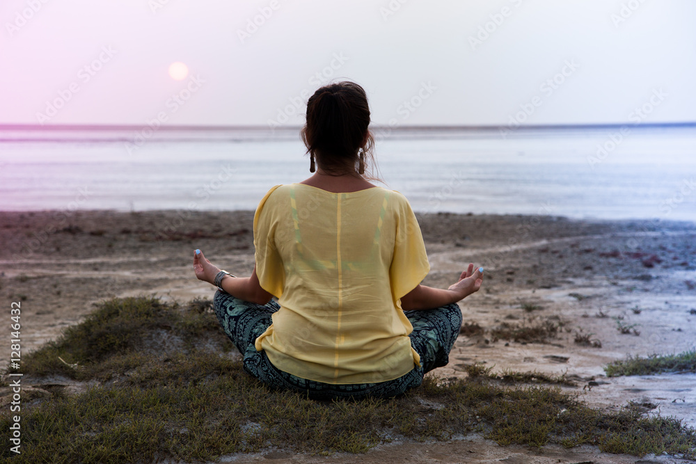 girl meditating at sunset. sits back, looks at the sun