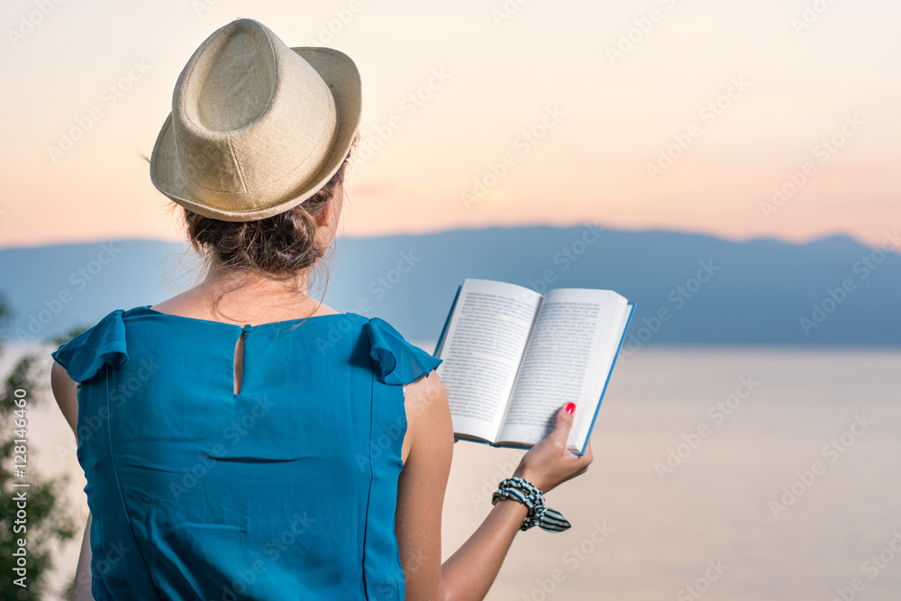 Woman reading a book with a sunset view