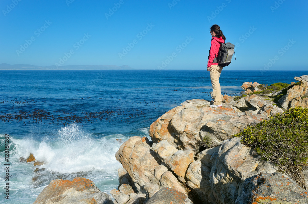 Woman looking at beautiful ocean view in Hermanus, hiking vacation and travel in South Africa
