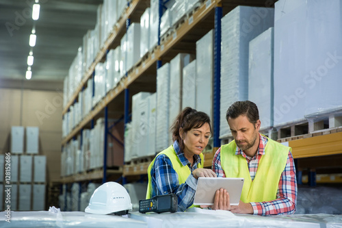 Man and a woman have short meeting in a warehouse and checking inventory levels of goods. First in first out, Last in last out, team working together concept photo. photo