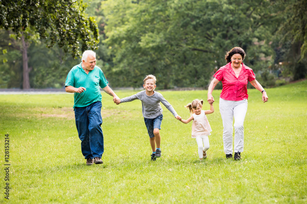 Grandparents And Grandchildren Running In Park Grandparents And Grandchildren Running In Park