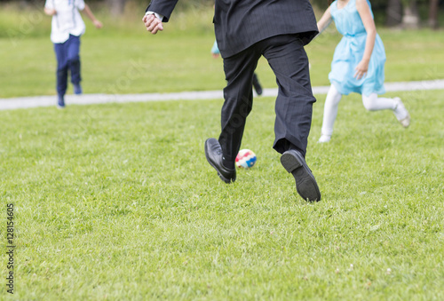 Grandfathers are playing football with their grandchildren. Children are enjoying the life in the summer.