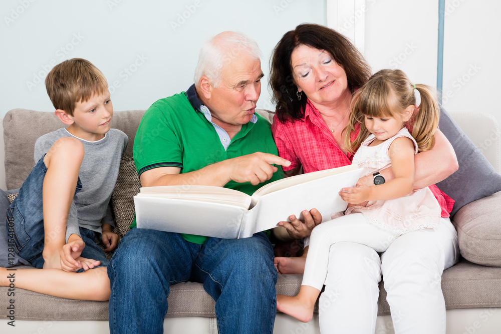 Grandparent And Grandchildren Looking At Photo Album Grandparent And Grandchildren Looking At Photo Album
