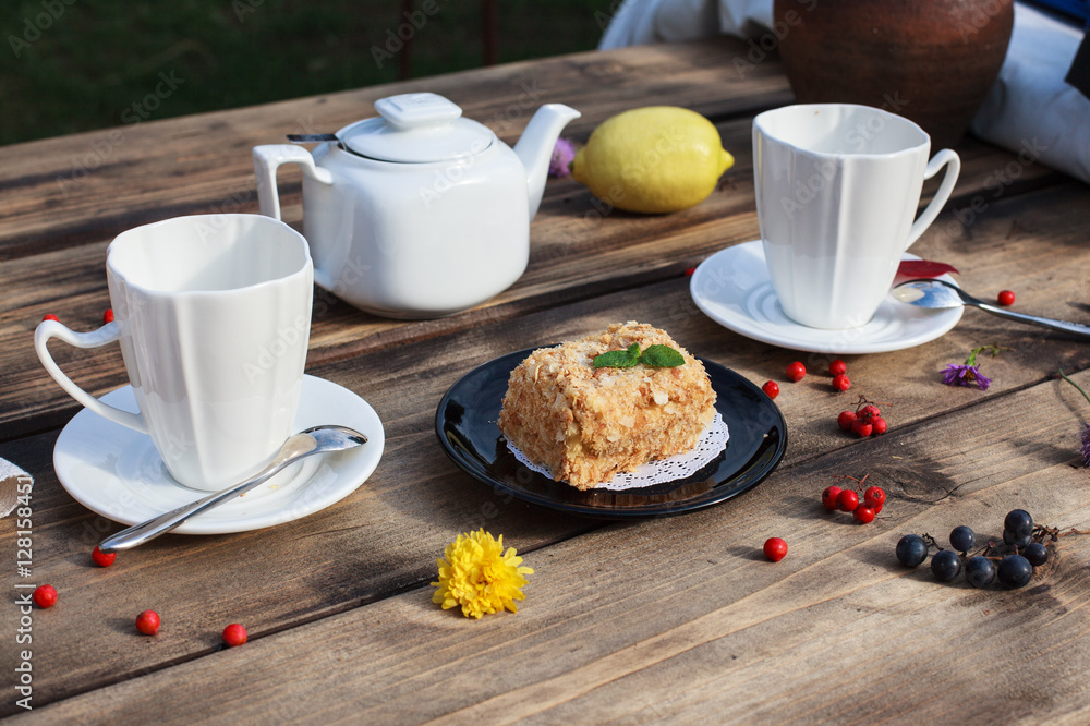 Cake on black plate and white tea pot served on wooden table
Cake on black plate and white tea pot served on wooden table