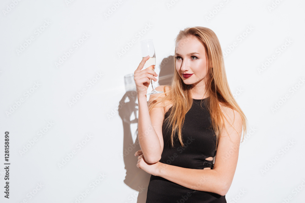 Smiling attrative young woman standing and drinking champagne Smiling attrative young woman standing and drinking champagne