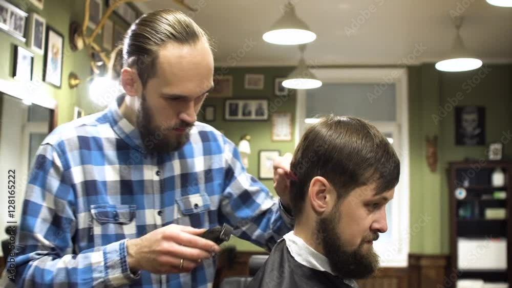 Concentrated Barber cutting hair with electric razor in barber shop Concentrated Barber cutting hair with electric razor in barber shop