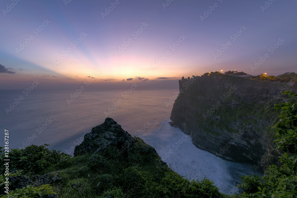 Pura Luhur Uluwatu Temple, Bali on cliffs above blue tropical sea at sunset