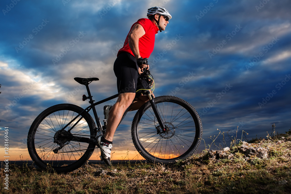 Young man cycling on a rural road through spring meadow Young man cycling on a rural road through spring meadow