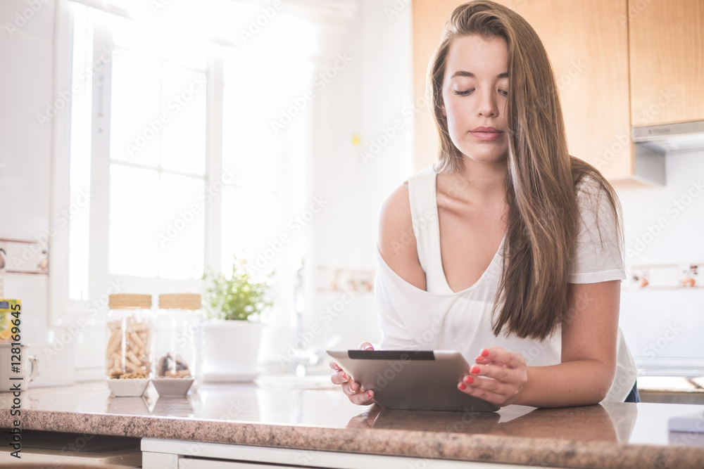 Young woman using tablet in kitchen Young woman using tablet in kitchen