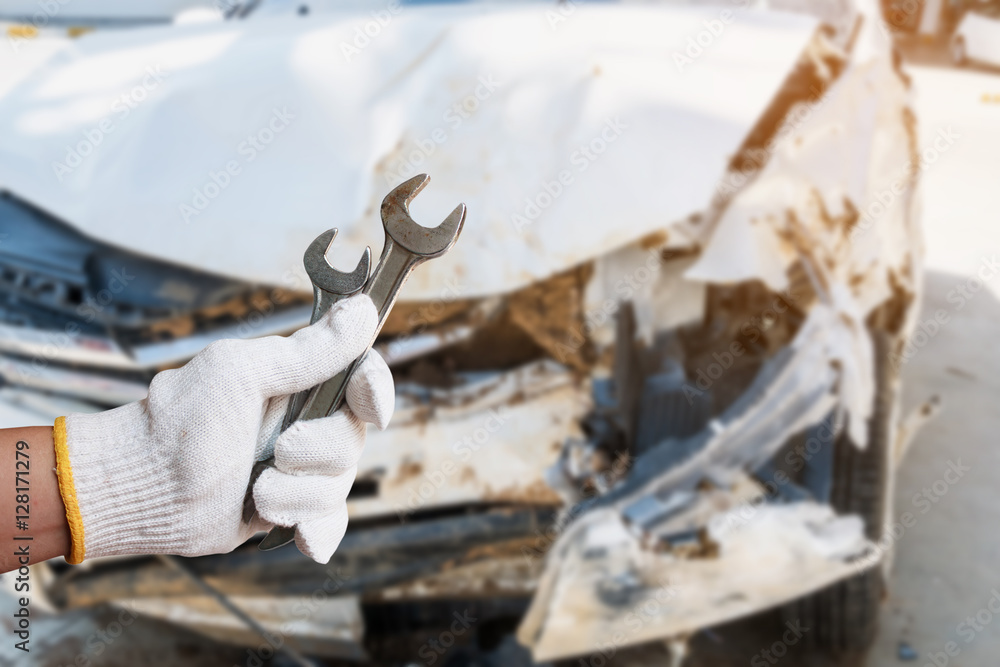 hand hold wrench with car crash damage background