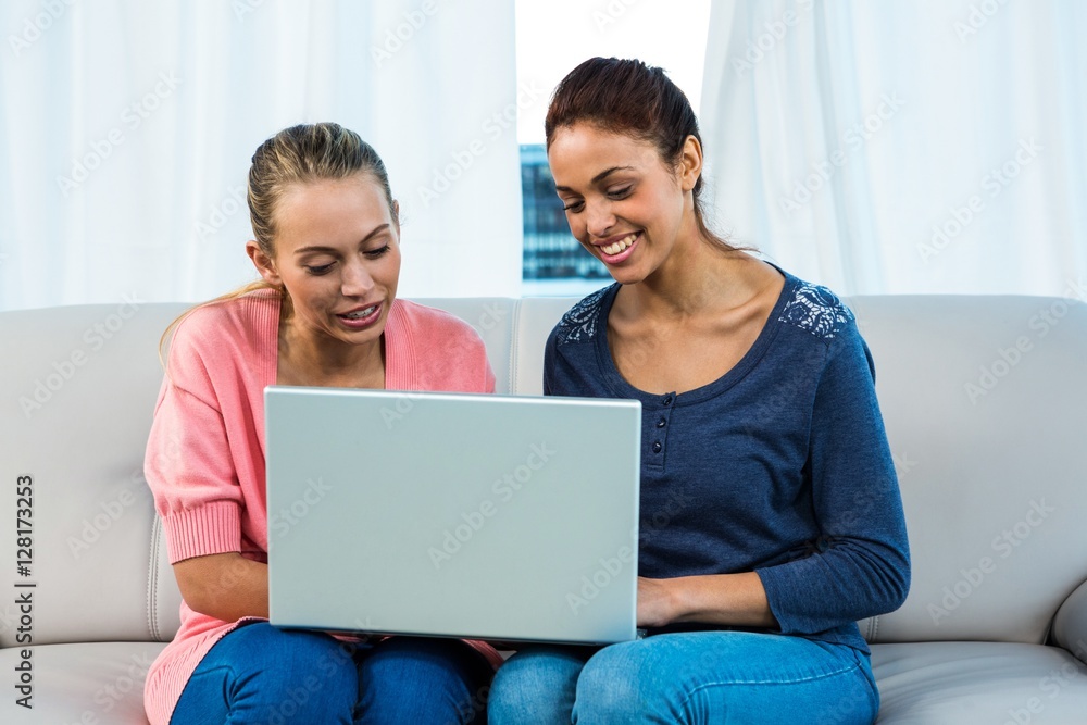 Friends using laptop on sofa Friends using laptop on sofa