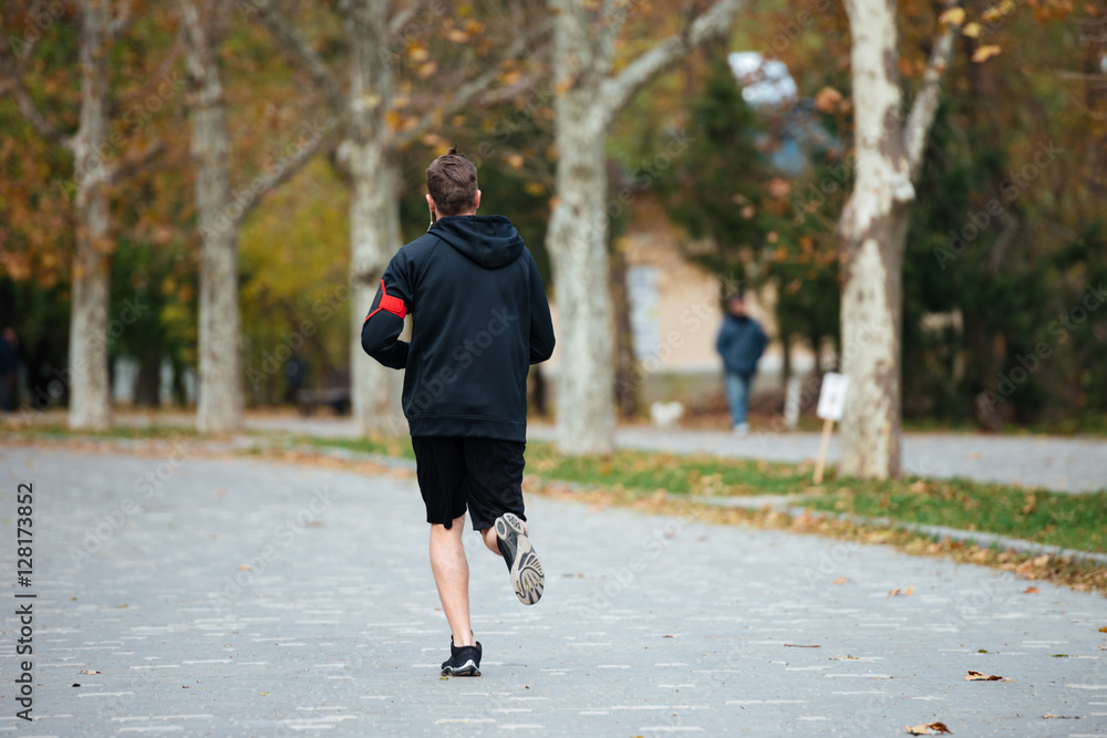 Fototapeta premium Back view of runner in park