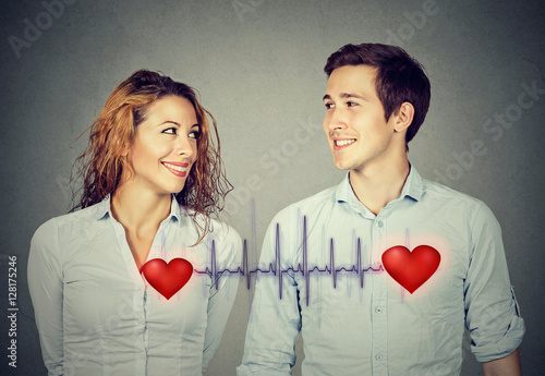 man woman looking at each other with red hearts linked by cardiogram