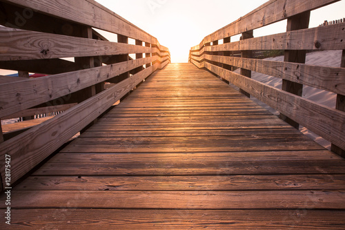 Fotografia wooden beach boardwalk path at sunset leading towards light