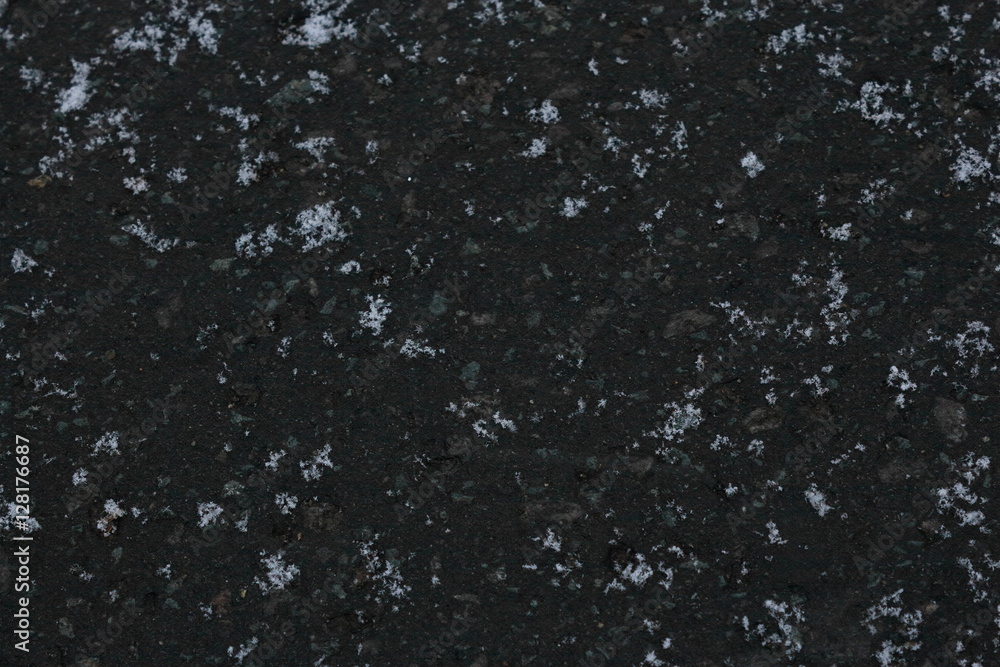 黒く凍ったアスファルトに落ちた雪