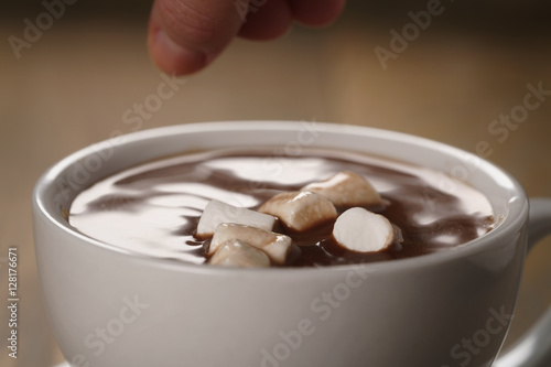 put marshmallows in cup of homemade hot chocolate , shallow focus