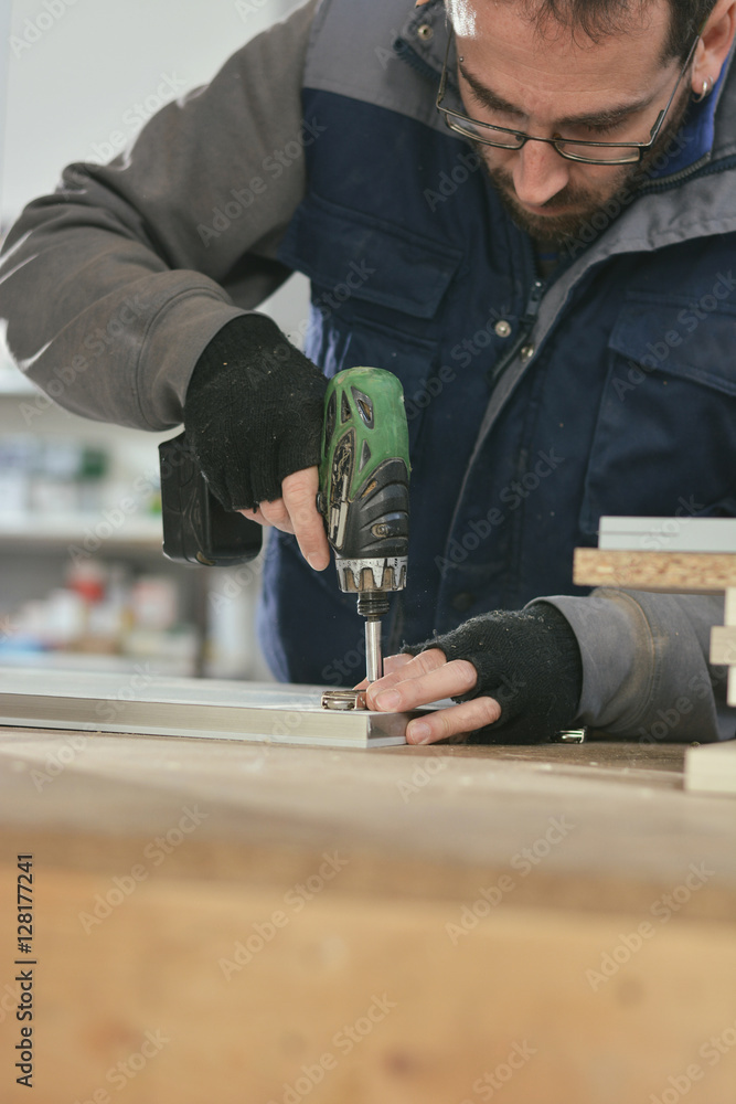 Carpenter fastening something to piece of furniture foto de Stock
