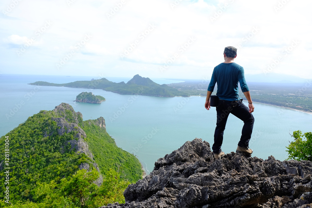 young traveler man standing on the top of mountain at Khao Lom Muak and enjoy the beauty of seascape, travel, freedom, Thailand. The winner, success