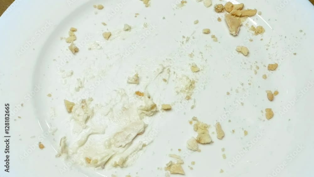 Piece of creamy sweet cake being cut with fork on white plate and eaten in a cafe restaurant. Close up shot. Piece of creamy sweet cake being cut with fork on white plate and eaten in a cafe restaurant. Close up shot.
