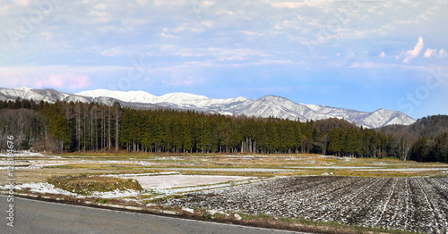 Alpine landscape of snow covered village and mountains on Honshu, Japan.  Villagers farm on the flat land at the base of the mountain range in the warmer months of the year. photo