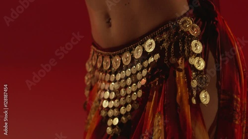 Beautiful traditional oriental belly dancer. Oriental girl dancing on red background. Studio shoot with fire. Shot on RED EPIC DRAGON Cinema Camera in slow motion. photo