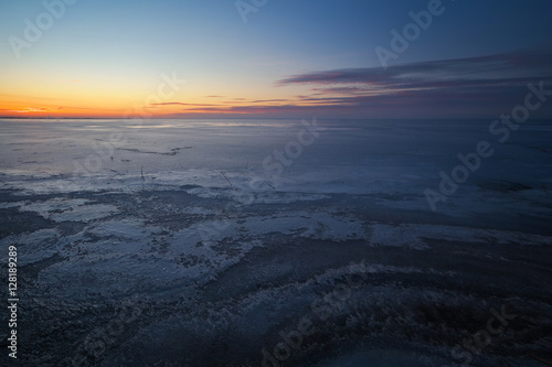 Beautiful winter landscape with frozen lake and sunset sky. 