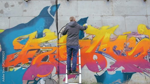 Graffiti artist painting on the wall, exterior