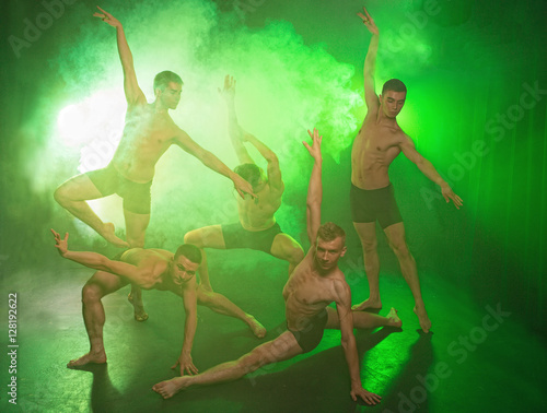A group of dancers young people while dancing in the Studio on the green smoky background © viktoriia1974