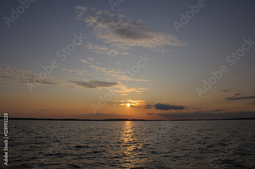 Beautiful sunset through small clouds over lake © serg269