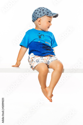 Blond boy sitting on the table, white background
